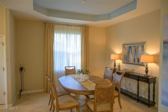 dining area featuring a raised ceiling and light tile patterned flooring