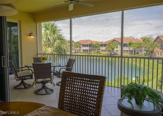 sunroom / solarium with ceiling fan and a water view