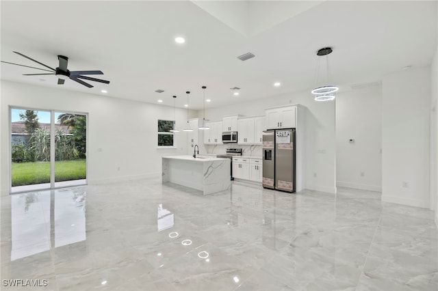 kitchen featuring appliances with stainless steel finishes, sink, white cabinetry, hanging light fixtures, and an island with sink