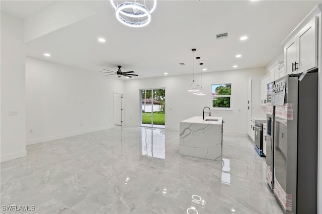 kitchen featuring stainless steel appliances, sink, a center island with sink, white cabinetry, and hanging light fixtures