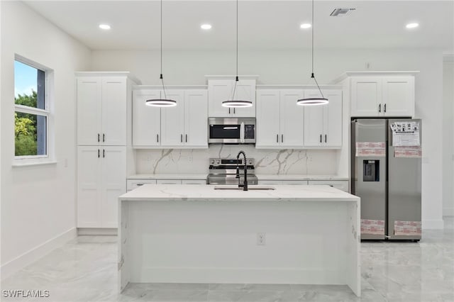 kitchen featuring decorative light fixtures, stainless steel appliances, white cabinetry, and a kitchen island with sink