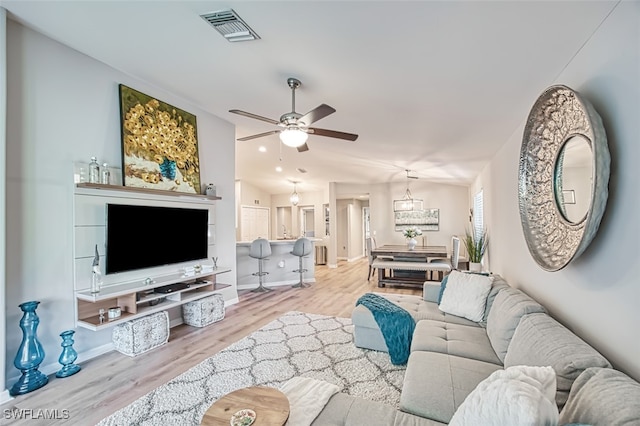 living room with ceiling fan, light wood-type flooring, and lofted ceiling