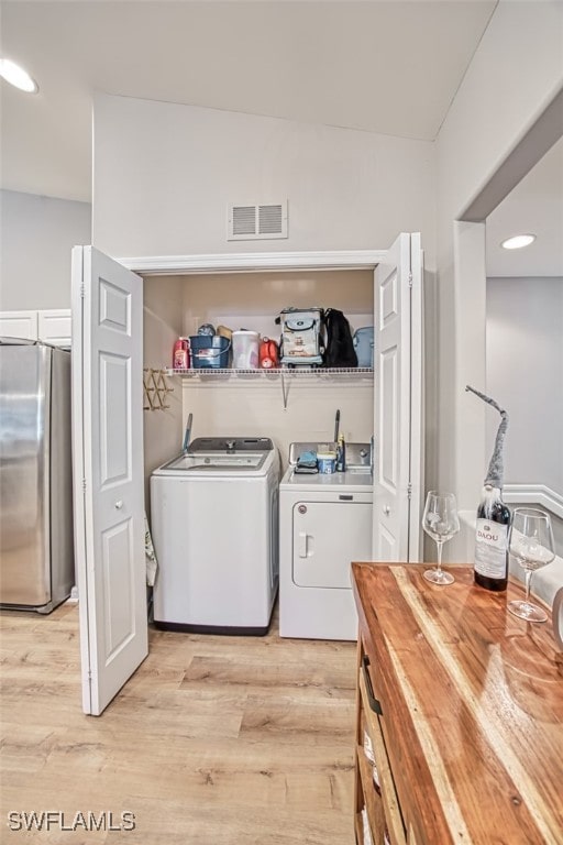 laundry area with washing machine and dryer and light hardwood / wood-style floors