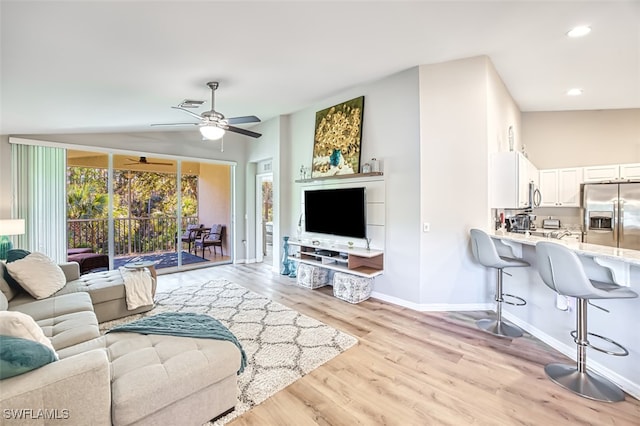 living room with ceiling fan, vaulted ceiling, and light hardwood / wood-style flooring