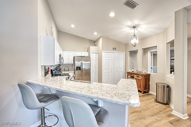 kitchen featuring pendant lighting, light hardwood / wood-style flooring, vaulted ceiling, white cabinetry, and stainless steel appliances