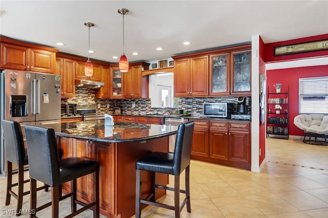 kitchen featuring a kitchen breakfast bar, stainless steel appliances, pendant lighting, light tile patterned floors, and a kitchen island