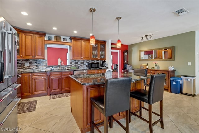 kitchen featuring a kitchen bar, dark stone countertops, a kitchen island, and hanging light fixtures