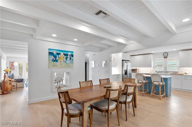 dining space featuring beam ceiling and light wood-type flooring