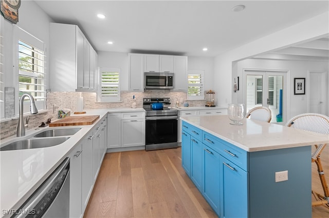 kitchen featuring stainless steel appliances, a wealth of natural light, a breakfast bar area, and sink