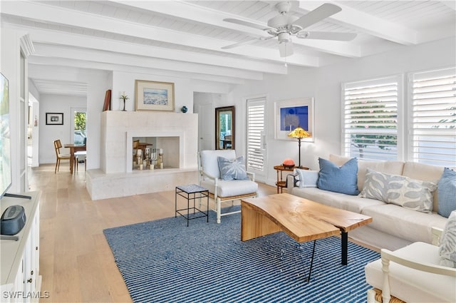 living room with beam ceiling, ceiling fan, a premium fireplace, light hardwood / wood-style flooring, and wood ceiling