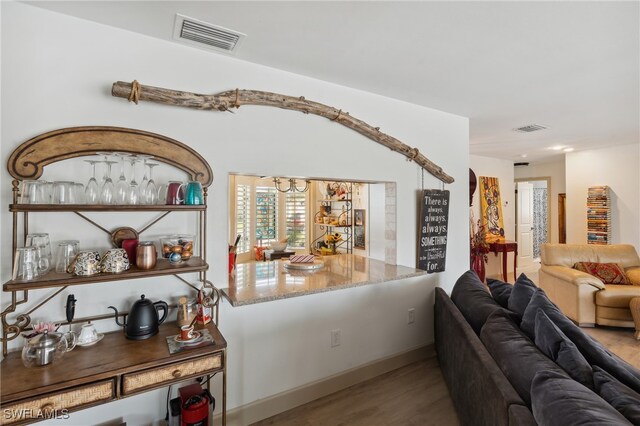 bar with light stone counters and light wood-type flooring