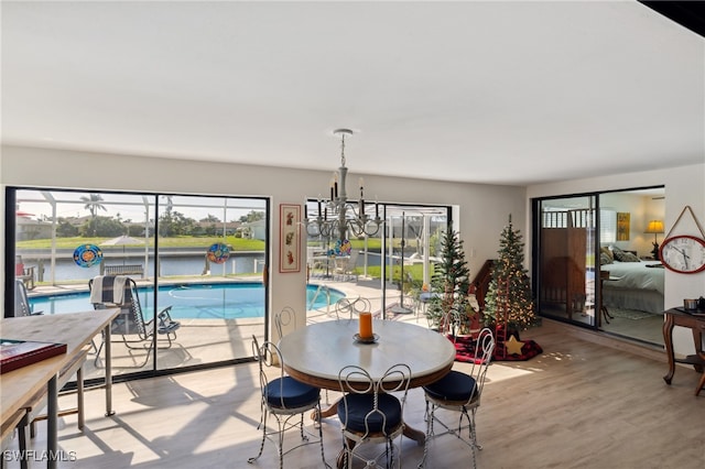 dining area featuring an inviting chandelier, a water view, light hardwood / wood-style flooring, and plenty of natural light