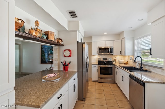 kitchen featuring backsplash, sink, light stone counters, white cabinetry, and stainless steel appliances