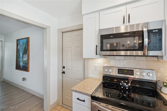 kitchen featuring light stone countertops, white cabinetry, stainless steel appliances, backsplash, and light hardwood / wood-style floors