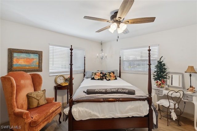 bedroom with multiple windows, ceiling fan with notable chandelier, and light wood-type flooring