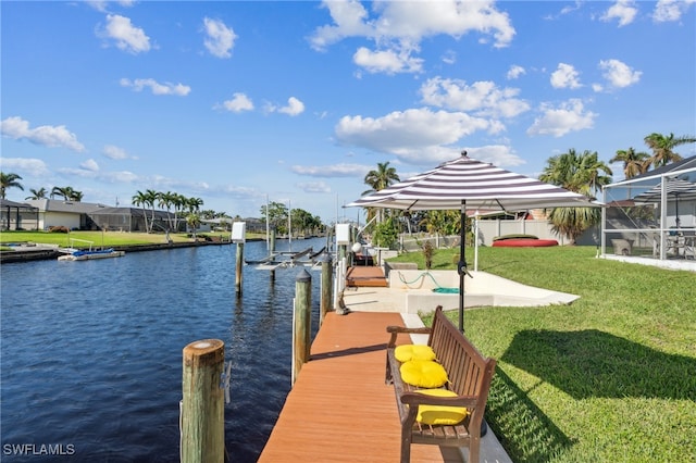 dock area with a lawn, glass enclosure, and a water view