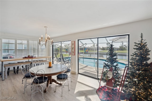 dining area with a water view, light hardwood / wood-style floors, and a notable chandelier