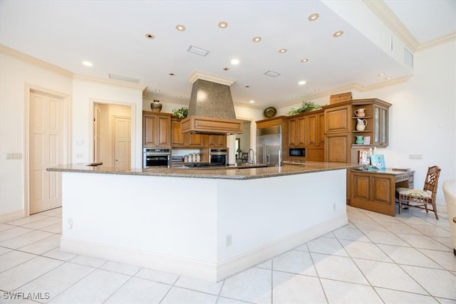 kitchen featuring a large island with sink, premium range hood, appliances with stainless steel finishes, and ornamental molding