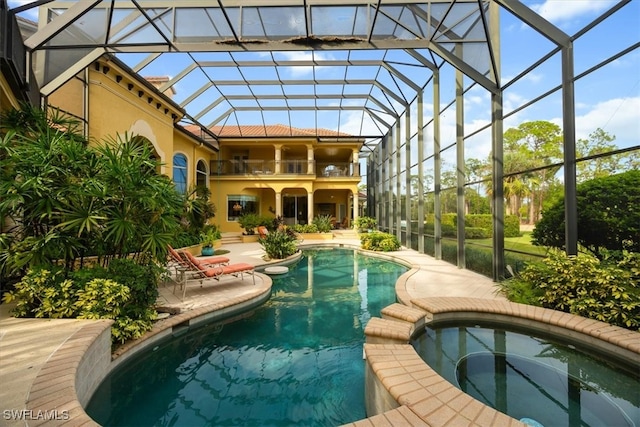 view of swimming pool featuring glass enclosure, a patio area, and an in ground hot tub