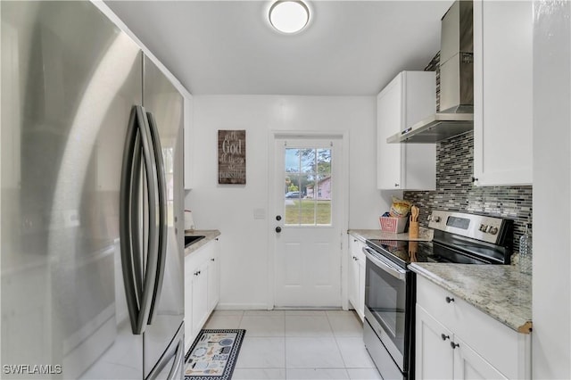 kitchen featuring light stone countertops, white cabinets, wall chimney range hood, and appliances with stainless steel finishes