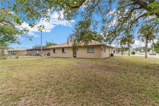 rear view of property featuring a lawn and central air condition unit