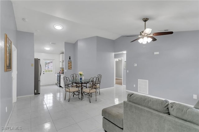 dining area with ceiling fan, light tile patterned floors, and vaulted ceiling