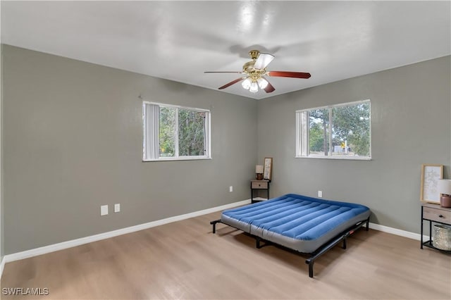 bedroom with ceiling fan, light hardwood / wood-style floors, and multiple windows