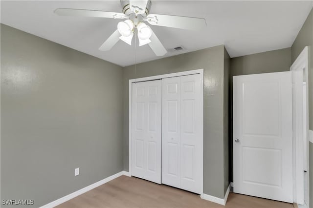 unfurnished bedroom featuring ceiling fan, light hardwood / wood-style floors, and a closet