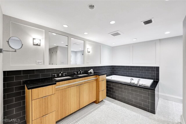 bathroom featuring tile patterned flooring, a washtub, vanity, and tasteful backsplash