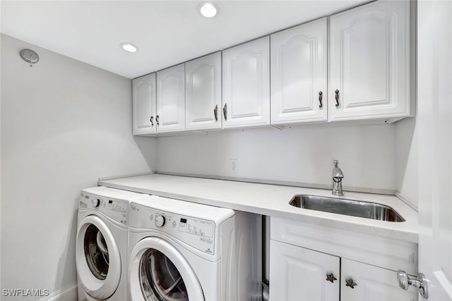 laundry room featuring washing machine and clothes dryer, cabinets, and sink