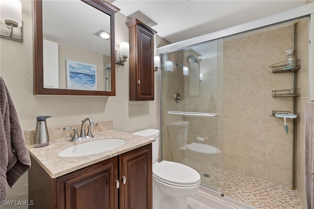 bathroom with vanity, toilet, and a shower with door