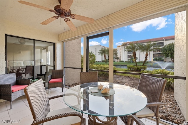 sunroom / solarium with ceiling fan and a water view