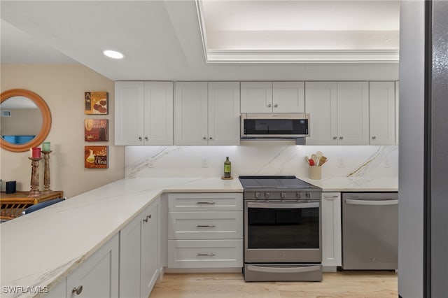 kitchen with light stone countertops, appliances with stainless steel finishes, tasteful backsplash, white cabinets, and light hardwood / wood-style floors