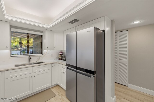 kitchen with stainless steel fridge, sink, and white cabinets