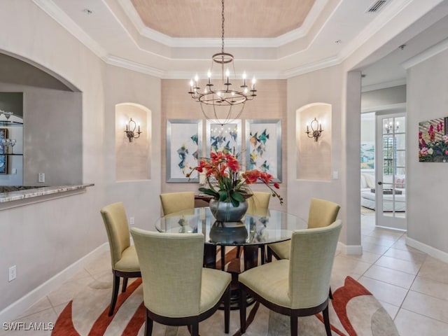 tiled dining space with a raised ceiling, crown molding, and a chandelier