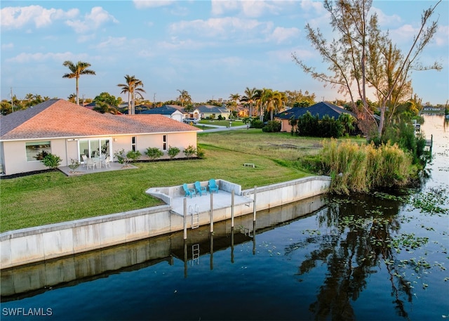 rear view of house featuring a lawn, a water view, and a patio