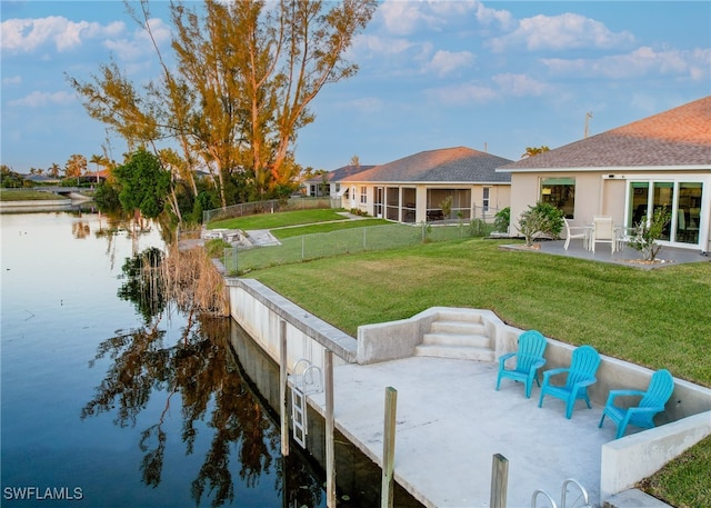 view of dock featuring a patio area, a water view, and a yard