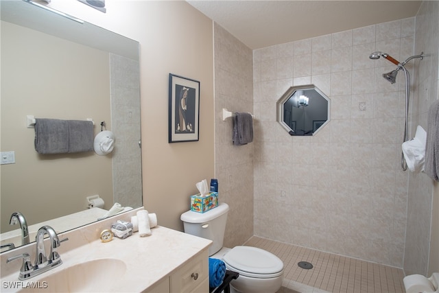 bathroom featuring tile patterned flooring, vanity, toilet, and a tile shower
