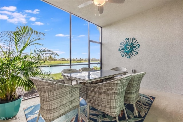 sunroom / solarium with ceiling fan and a water view