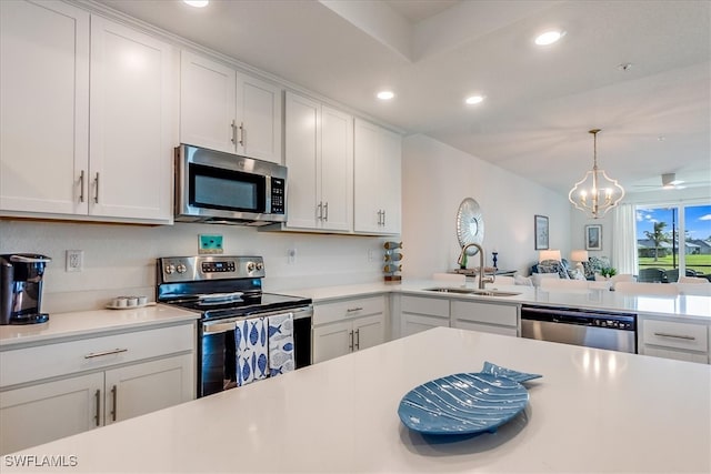 kitchen featuring appliances with stainless steel finishes, sink, white cabinets, a chandelier, and hanging light fixtures