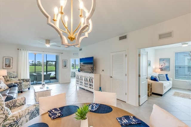 tiled living room with ceiling fan with notable chandelier