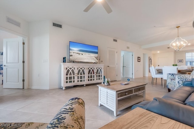 tiled living room with ceiling fan with notable chandelier