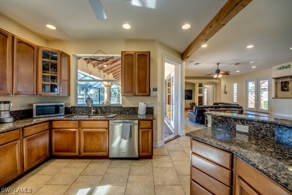 kitchen with appliances with stainless steel finishes, french doors, dark stone countertops, and sink