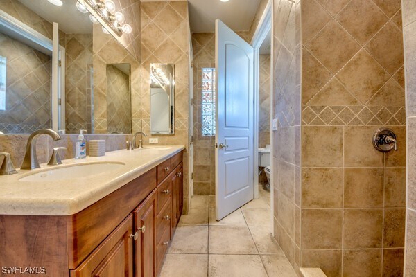 bathroom featuring tile patterned flooring, vanity, and tile walls