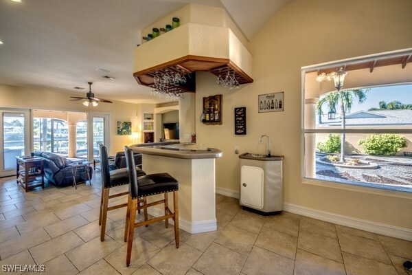 kitchen featuring a kitchen bar, kitchen peninsula, ceiling fan, and light tile patterned floors