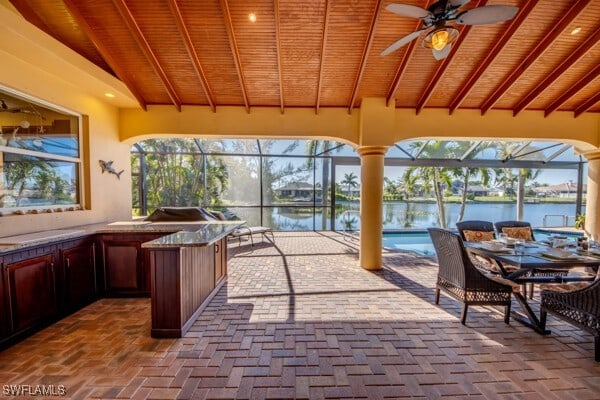 sunroom featuring lofted ceiling with beams, a water view, ceiling fan, and wooden ceiling