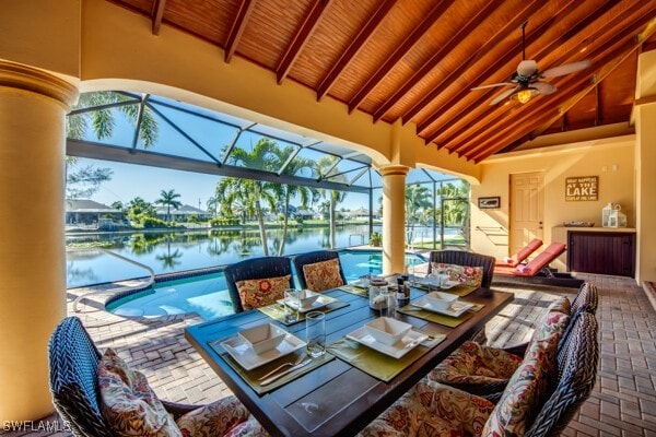 sunroom with lofted ceiling with beams, a healthy amount of sunlight, a water view, and a swimming pool