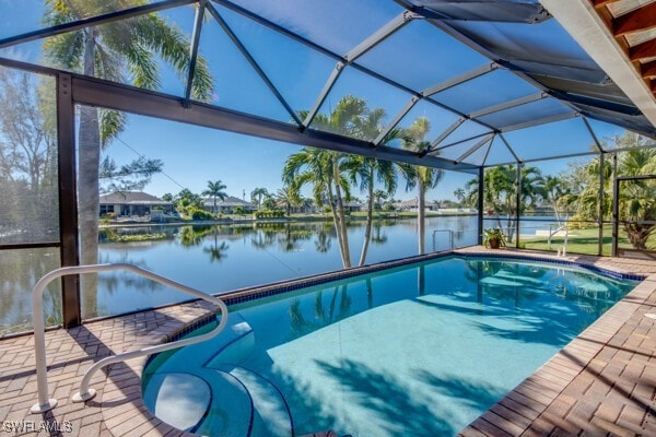 view of pool with a water view, glass enclosure, and a patio area