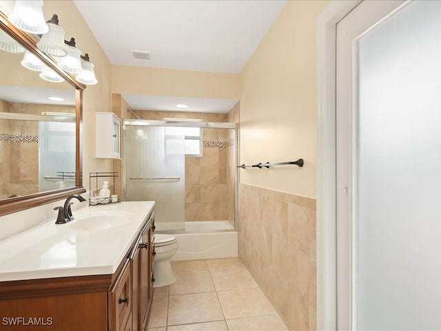 full bathroom with tile patterned floors, vanity, toilet, and bath / shower combo with glass door