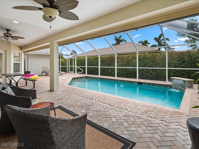 view of swimming pool featuring pool water feature, glass enclosure, ceiling fan, and a patio area